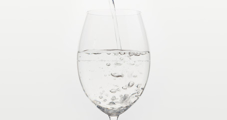 pouring water into wine glass over white background