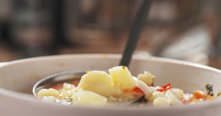 closeup scooping cauliflower soup from bowl on wood table