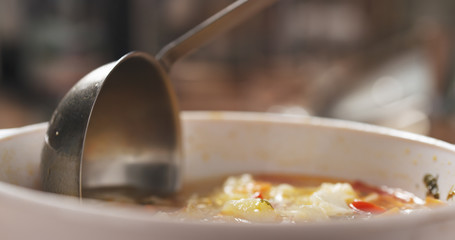 closeup scooping cauliflower soup from bowl on wood table