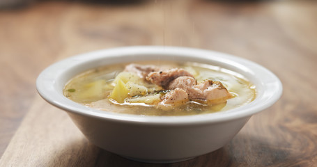 closeup seasoning with pepper fish soup with salmon on wood table