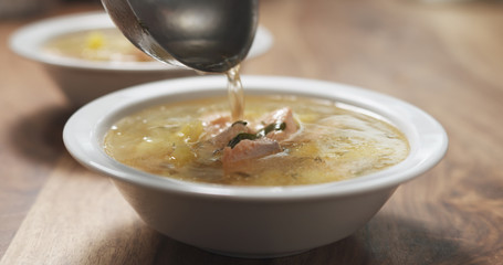 closeup pour fish soup with salmon into bowl