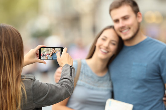 Friends taking photos with a smart phone on the street