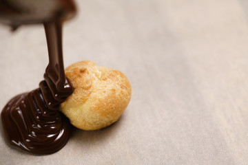 pouring dark chocolate on profiterole on parchment paper