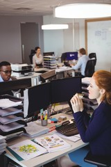 Businesswoman eating snack while colleagues working in creative