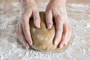 hands holding dough on a wooden table