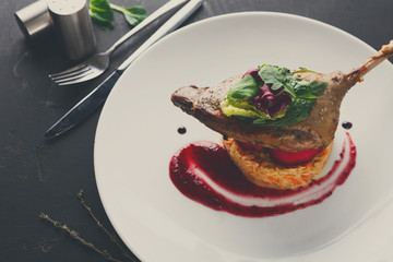 Restaurant meals. Duck confit with vegetables on black backgroun