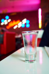 glass of iced vodka is on the table in the club on red interior