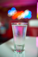 glass of iced vodka is on the table in the club on red interior