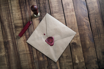 Blank vintage envelope, sealing wax and stamp on wood table background. Responsive design mock up....