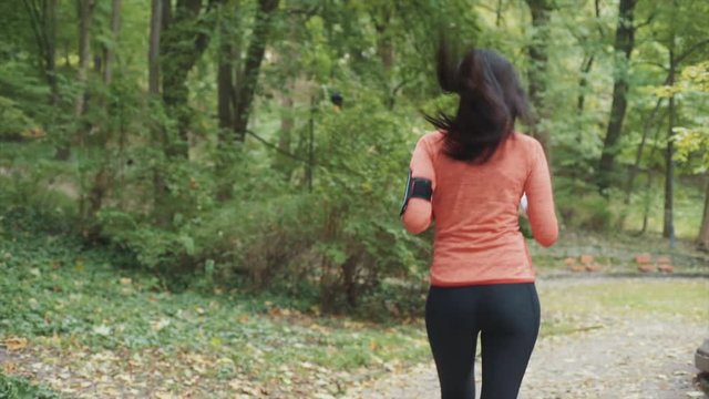 Young woman running in the park. Frame from behind