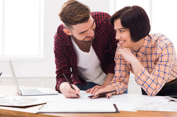 Two smiling architects discussing building plan