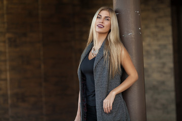 Outdoor portrait of pretty beautiful woman with blonde hair wearing necklace. Stylish girl at street.