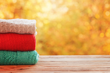 Stack pile of knitted autumn clothes on nature background.