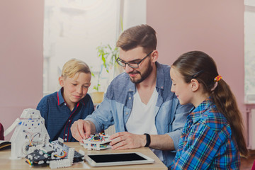 Fototapeta premium Stem education. Kids creating robots with teacher