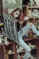 Bloody young woman at the yard with creepy toys. halloween make up