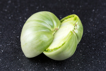 Fresh sliced green tomatoes on a black background