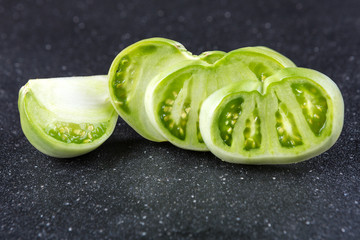 Fresh sliced green tomatoes on a black background