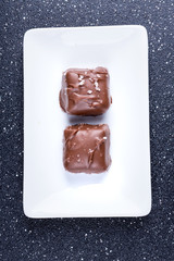Two salted chocolate caramels on a black background