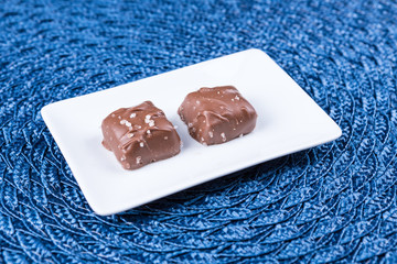 Two salted chocolate caramels on a woven mat