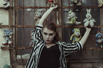 Bloody young woman at the yard with creepy toys. halloween make up