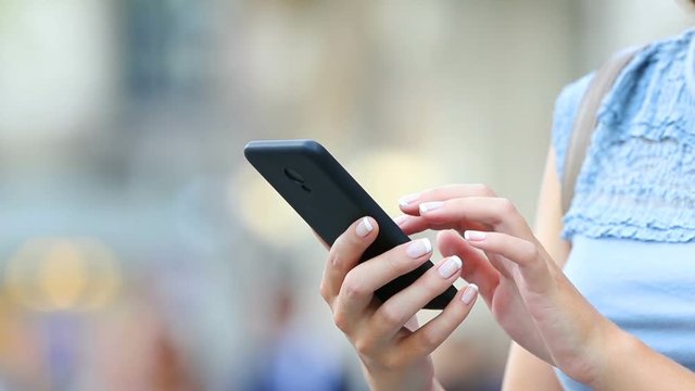 Close up of woman hands using a smart phone searching content on the street