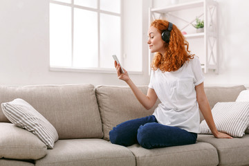 Young woman in headphones on beige couch