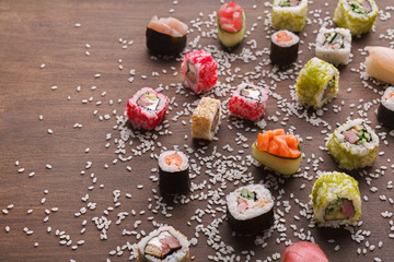 Set of sushi, maki and rolls with sesame on wooden rustic background