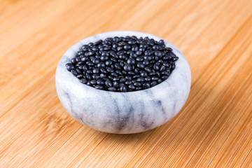 Black beluga lentils on a wood background