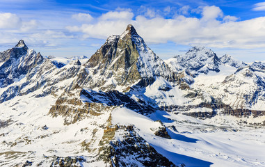 Panorama scenic view on snowy Matterhorn peak in sunny day with blue sky and clouds in background,...