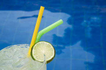 Closeup of cocktail at the edge of the outdoor swimming pool