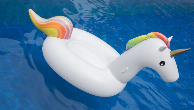 Top view of inflatable white unicorn float in the outdoor swimming pool