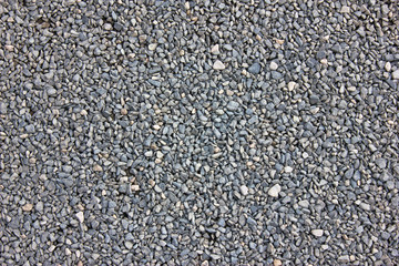 Texture of gray gravel. Grey stony floor. A wall of gray gravel. Stones small and medium-sized. Sharp edges of the stones. Sand and stones on the floor. The land is covered with stones