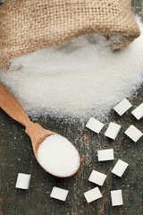 White sugar in sack and spoon on wooden table