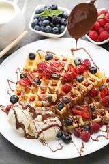 Sweet waffle with berries and ice cream on grey wooden table