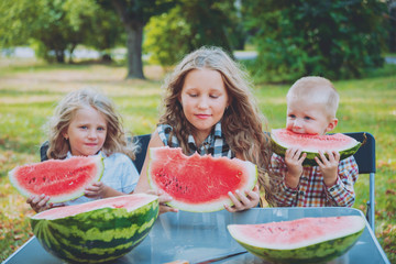 Big family with children eating watermelon.