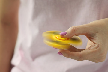 Female hand holding yellow fidget spinner toy