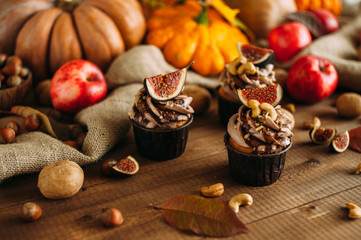 Obraz na płótnie Canvas Autumn tasty cupcakes with ginger and chocolate on a wooden background of autumn harvest. Pumpkins, patsons, apples, nuts.