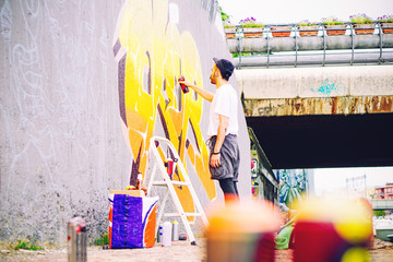 Street artist painting a colorful graffiti 
