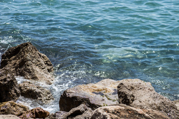 Sea waves crashing over rocks on wild stone beach.