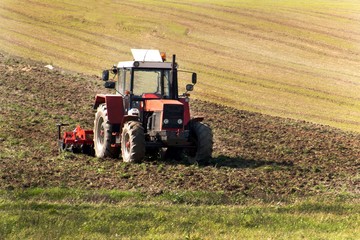 Red tractor in the field. Agricultural farm work. Agriculture in the Czech Republic.