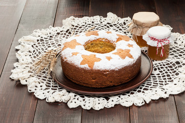 homemade traditional fruit cake on clay plate decorated with wheat ears and honey jars at wooden table