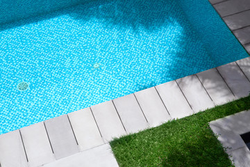 view of summer time swimming pool with grass and tiles around