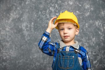 A boy holds onto a construction helmet and smiling