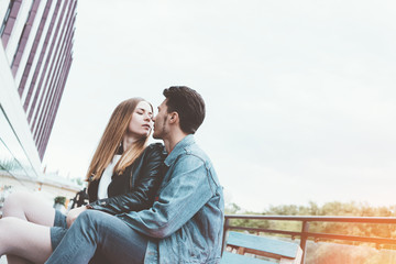 Young beautiful couple lovers sitting together, huging, kissing and enjoying good weather.