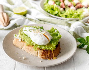 Toast with lettuce and poached egg on the wooden background