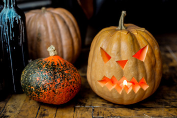 Family of Halloween pumpkin head jack lantern near candlestick bottles on black leather armchair...