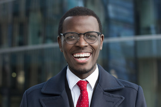 Close up portrait of successful confident african american corporate executive business man. Happy smiling black businessman standing against office building.