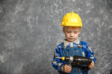 Boy in hard hat with drill, screwdriver in hand