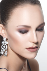 Beauty portrait of a beautiful girl with evening make-up and elegant earrings.