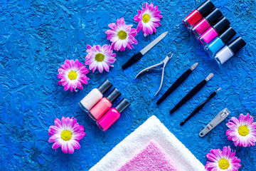 Obraz na płótnie Canvas Manicure in beauty salon. Tools for manicure, nail polishes and towels on blue desk top view